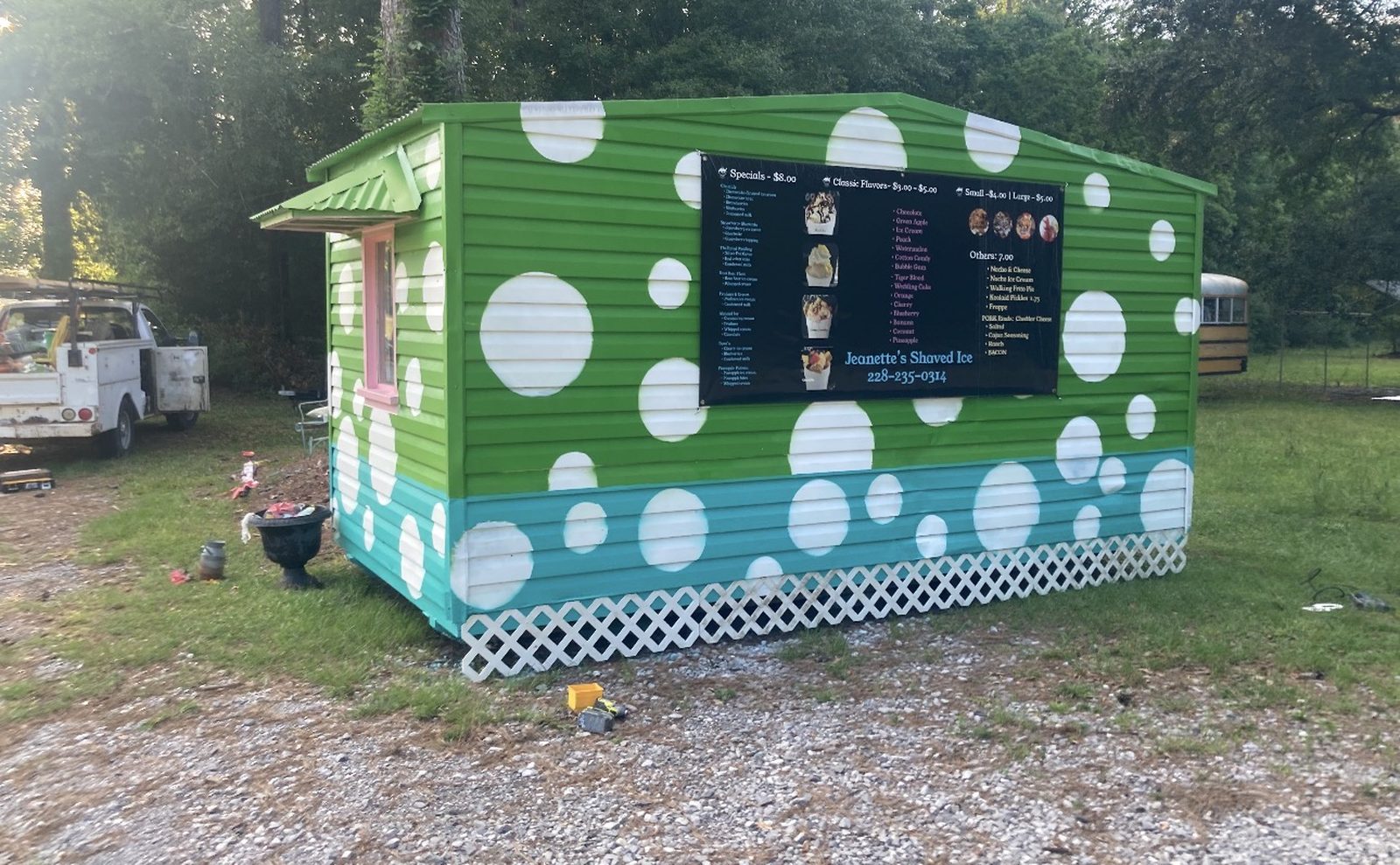 The little green polka-dot Ms. Jeanette's Shaved Ice stand with its menu board